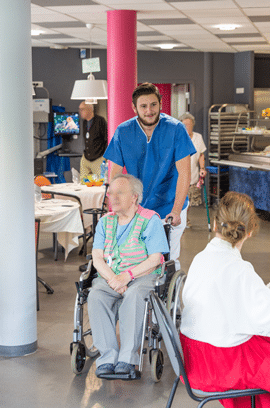 Aide soignant transportant une résidente en fauteuil roulant au Centre de soins de Betharram